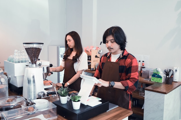 Dois garçom de café e barista trabalhando