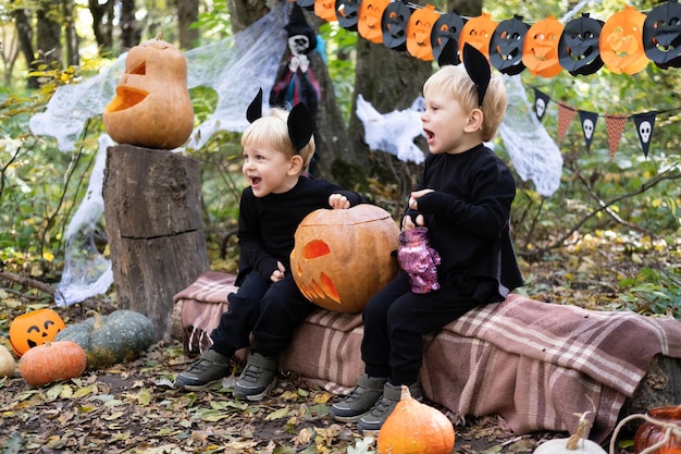 dois gêmeos felizes meninos crianças em trajes de halloween se divertindo em decorações de halloween ao ar livre