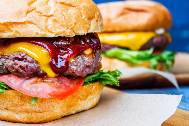 Dois hambúrgueres de carne com legumes, queijo e molho close-up.