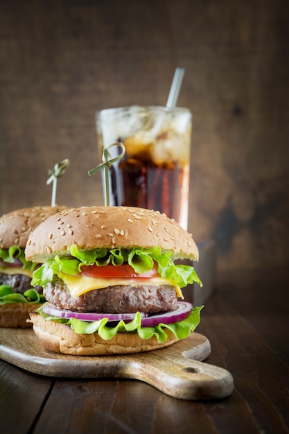 Dois hambúrgueres de carne fresca com cola na placa de madeira