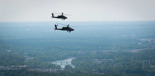 Dois helicópteros sobrevoam uma cidade com um rio ao fundo