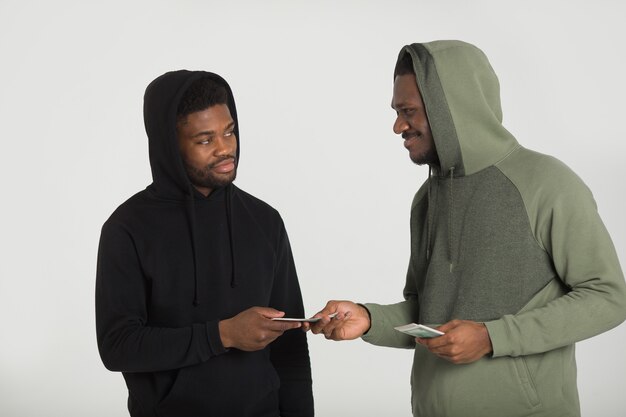 Dois homens africanos desportivos com fatos de treino em um fundo branco com dólares nas mãos