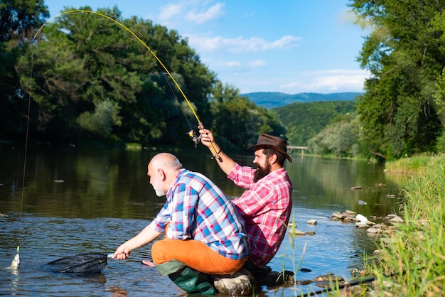 Dois homens amigos pescador pescando no rio velho pai e filho com vara de pesca em recreação ribeirinha