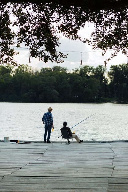 Dois homens apreciando a vista do rio e pescando