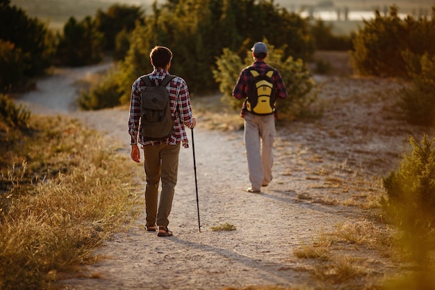 Dois homens caminhantes desfrutam de um passeio na natureza ao pôr do sol no verão