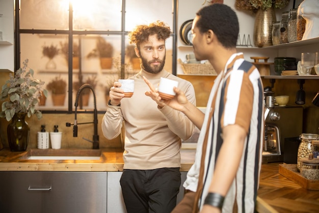 Dois homens conversando e tomando café na cozinha em casa