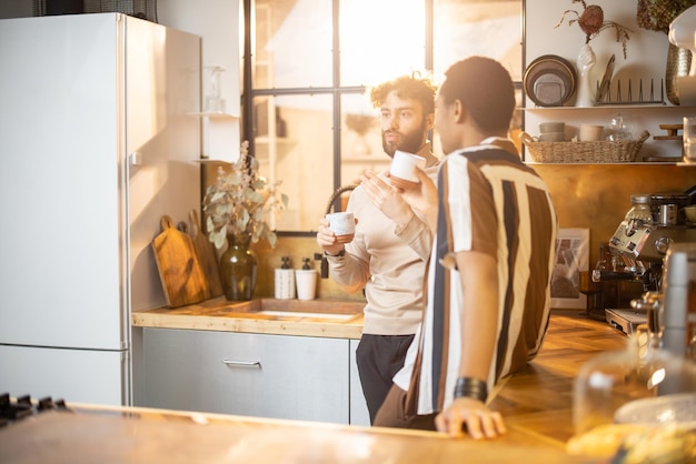 Dois homens conversando e tomando café na cozinha em casa