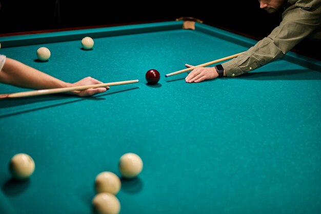 Dois homens cortados jogando sinuca ou se preparando para atirar bolas de bilhar na mesa de bilhar