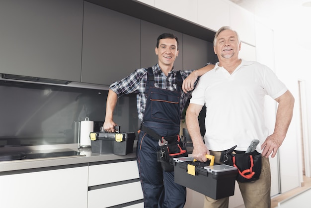 Dois homens de encanador estão na cozinha.