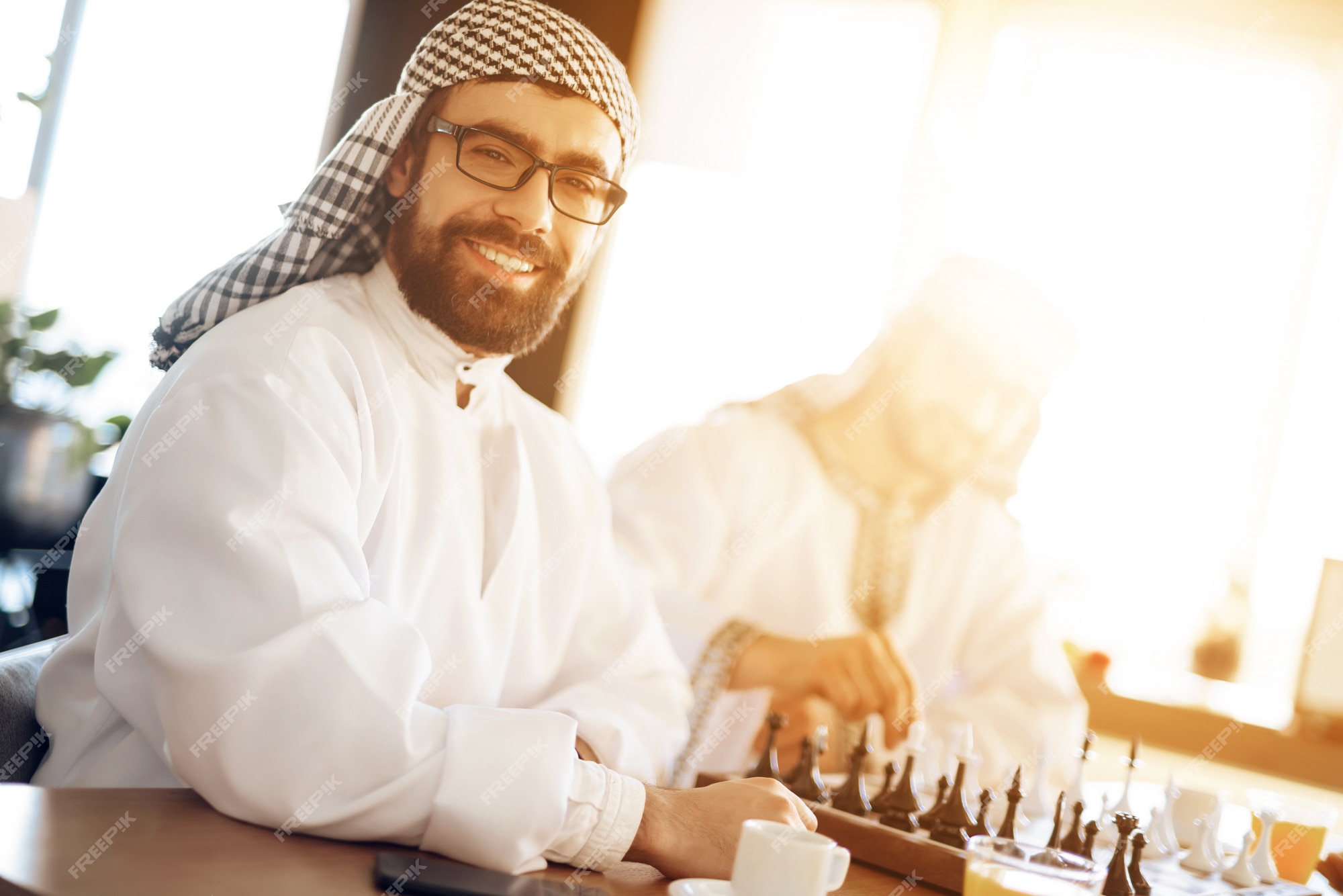 Homem de negócios árabe que joga a xadrez na tabela na sala de