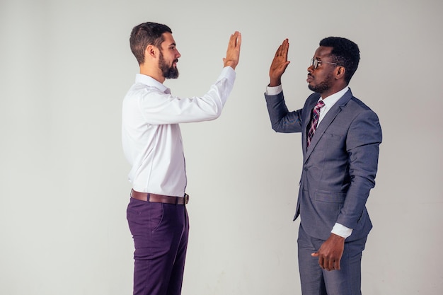 Dois homens de negócios confiantes falando alto cinco empresa internacional de trabalho em equipe good deal.afro homem americano e europeu no estúdio em fundo branco.