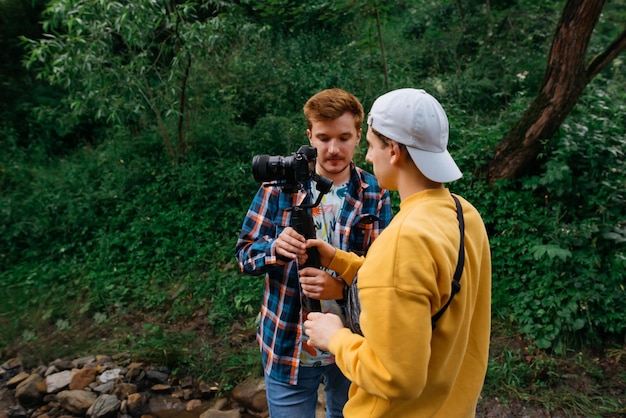 Dois homens ficam na floresta com uma câmera no gimbal e criam conteúdo para um blog de viagens