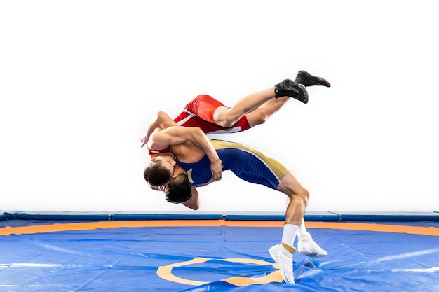 Dois homens fortes em meia-calça de luta livre azul e vermelha estão lutando e fazendo uma luta suplex em um tapete de luta amarelo
