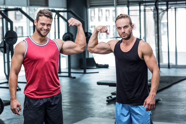 Dois homens musculosos flexionando o bíceps