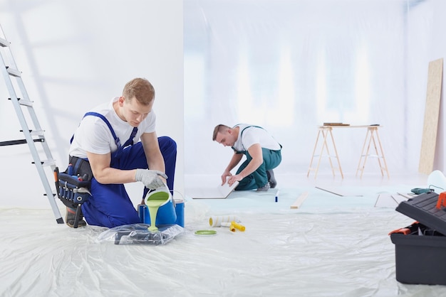 Dois homens pintando uma parede em uma sala