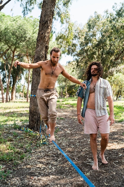 Dois homens praticando slackline no parque da cidade durante o verão