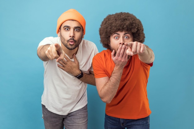 Dois homens surpresos surpresos olhando para a câmera com olhos grandes, apontando para a câmera com os dedos