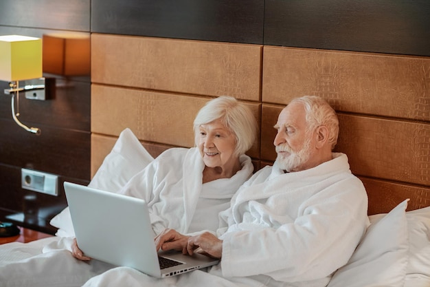 Dois idosos assistindo algo no laptop e parecendo interessados