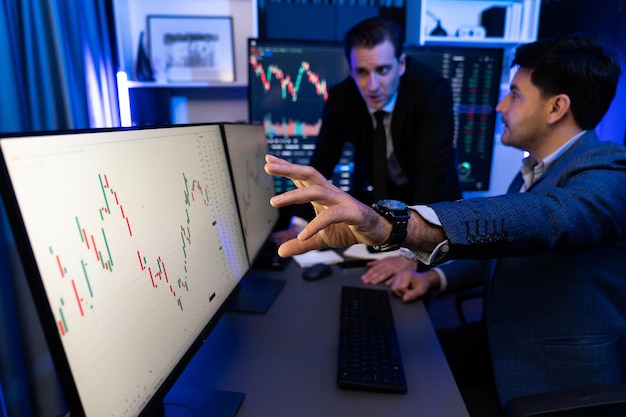 Dois investidores de ações apontando ações de mercado de interesse na tela do monitor vendíveis