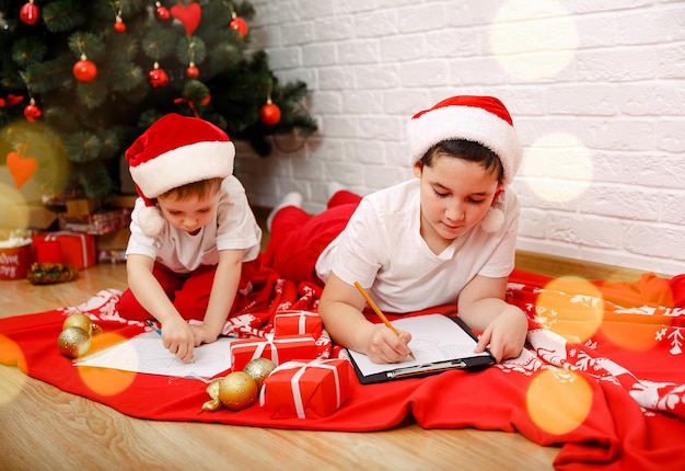 Foto dois irmãos bonitos a escrever uma carta ao pai natal no ano novo.