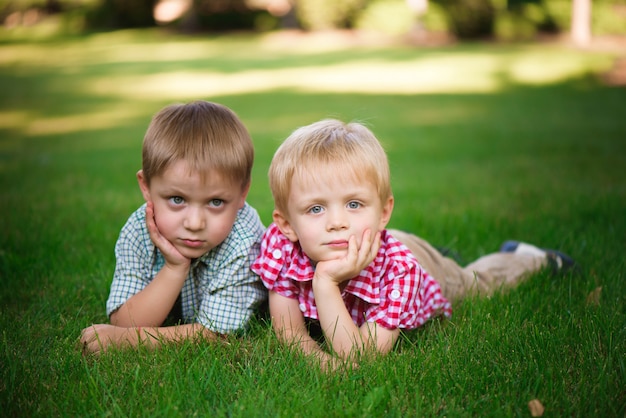 Dois irmãos, deitado na grama em um parque ao ar livre, sorrindo e