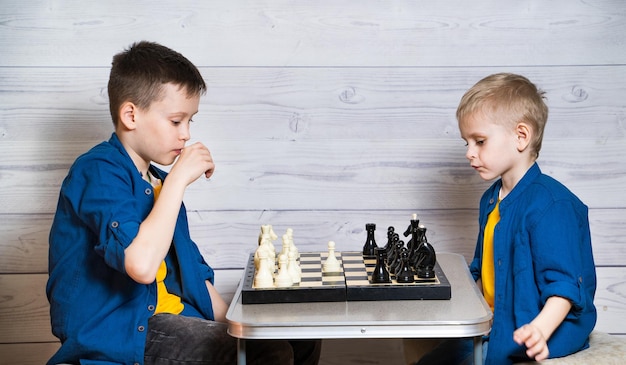 Dois irmãos estão jogando xadrez em um fundo de madeira leve Jogos e atividades para crianças Conceito de família