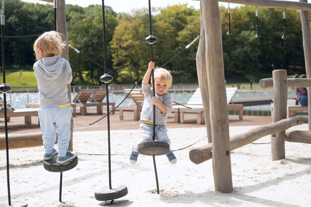 Dois irmãos gêmeos de meninos criança brincando no parque infantil em um dia ensolarado de outono.