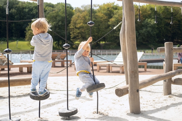 Dois irmãos gêmeos de meninos criança brincando no parque infantil em um dia ensolarado de outono.