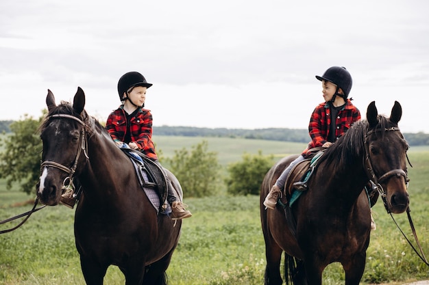 Dois irmãos meninos andando a cavalo