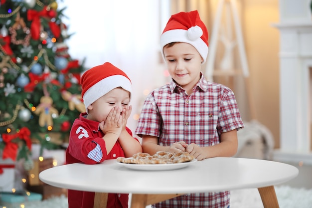 Dois irmãos pequenos fofos comendo biscoitos na decoração de natal