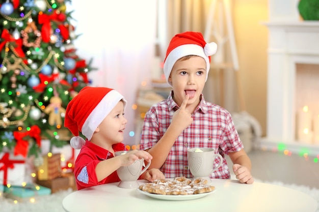 Dois irmãos pequenos fofos comendo biscoitos no fundo da decoração de Natal