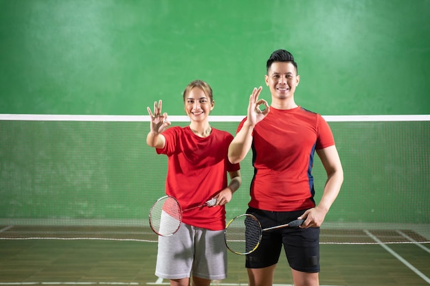 Dois jogadores de badminton em pé com gesto de mão bem