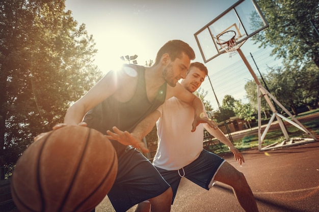 Dois jogadores de basquete de rua jogando um contra um. Eles estão fazendo uma boa ação e guardando a bola.