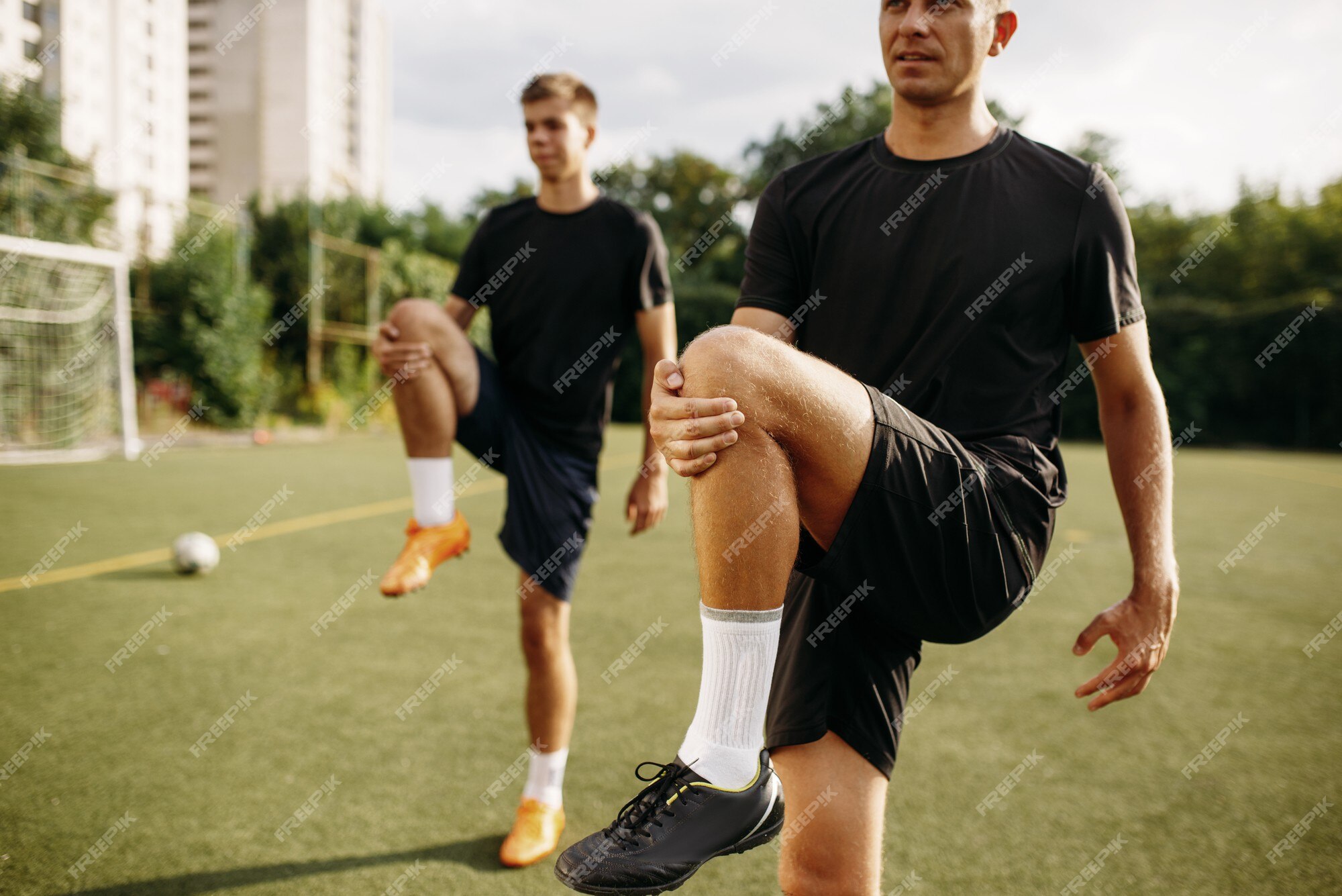 Dois jogadores de futebol fazendo exercícios de alongamento no campo.  treinamento de futebol em estádio ao ar livre, treino em equipe antes do  jogo