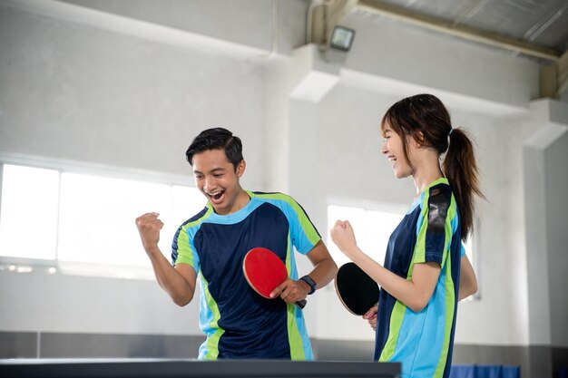 Foto dois jogadores de pingue-pongue competem com os punhos enquanto pontuam na mesa de pingue-pong