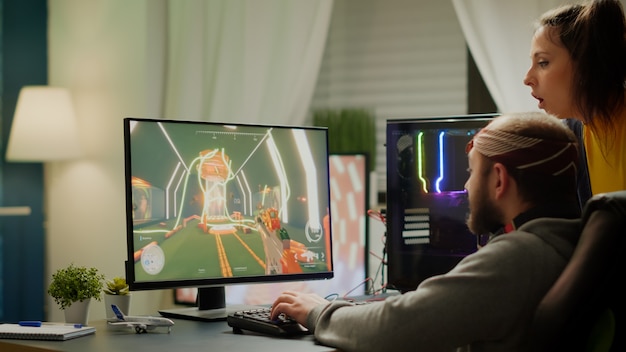 Foto dois jogadores jogando videogame de tiro em primeira pessoa no poderoso computador rgb gritando, apoiando-se mutuamente durante a competição online. homem cibernético profissional se apresentando em casa em um torneio virtual