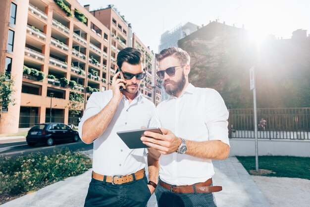 Dois, jovem, modernos, homem negócios, usando, dispositivos