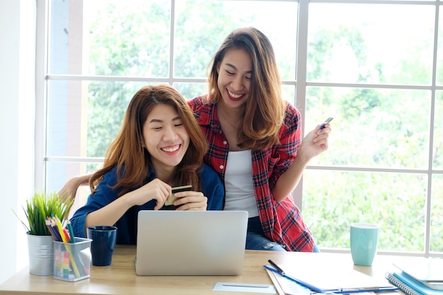 Dois, jovem, mulheres asian, segurando, cartão crédito, e, usando, computador laptop, para, shopping linha