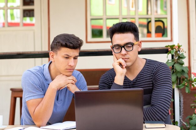 Dois jovens adultos concentrados em um laptop colocado em uma mesa Estudantes e negócios