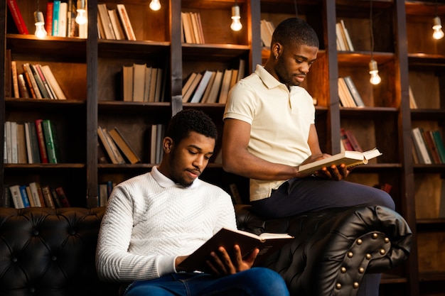 dois jovens africanos estão sentados no sofá com livros