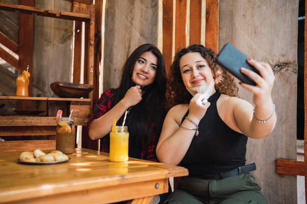 Dois jovens amigos adoráveis e felizes tiram uma selfie em um bar.