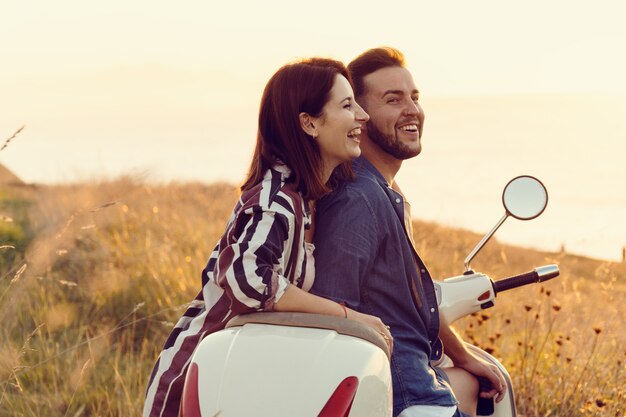 Foto dois jovens amigos se divertindo e sorrindo em uma motocicleta