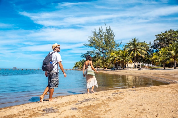 Dois jovens caminhando ao longo da praia de sandy bay em roatan island honduras