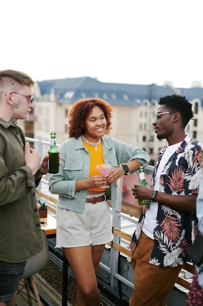 Dois jovens casais interculturais em roupas casuais elegantes tomando bebidas e conversando