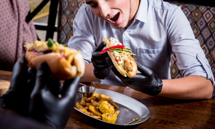Foto dois jovens com fome comendo cachorro-quente no café. restaurante