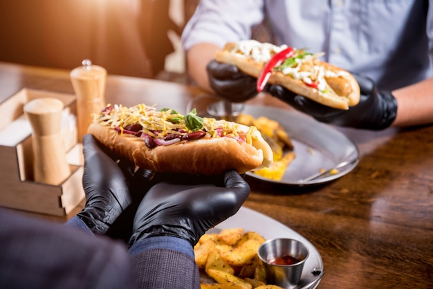 Dois jovens com fome comendo cachorro-quente no café. Restaurante