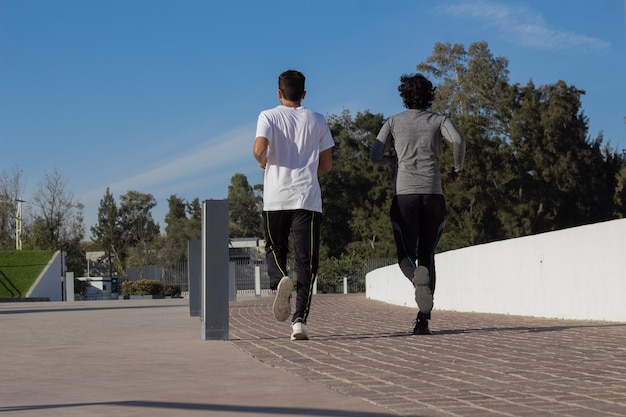 Dois jovens corredores masculinos latinos treinando juntos no parque ao sol da manhã