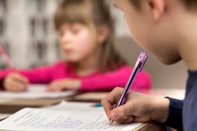 Dois jovens crianças bonitos, menino e menina, irmão e irmã fazendo lição de casa, escrevendo e desenhando em casa. arte educação, criatividade e crianças atividades conceito.