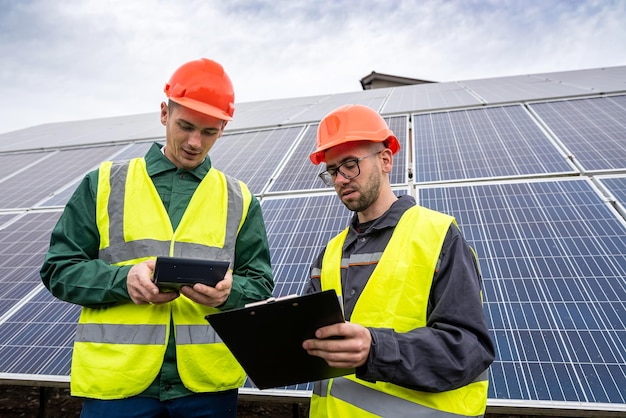 Dois jovens em capacetes especiais fazem anotações depois de inspecionar os painéis solares