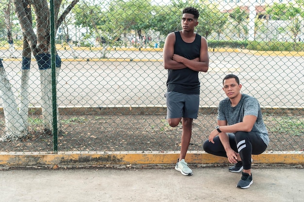 Dois jovens em roupas esportivas relaxando ao ar livre olhando para a câmera